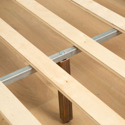Wooden bed slats with metal support frame on light wood floor.