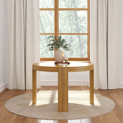 Round wooden table with modern decoration in a cozy room with natural light and elegant curtains.