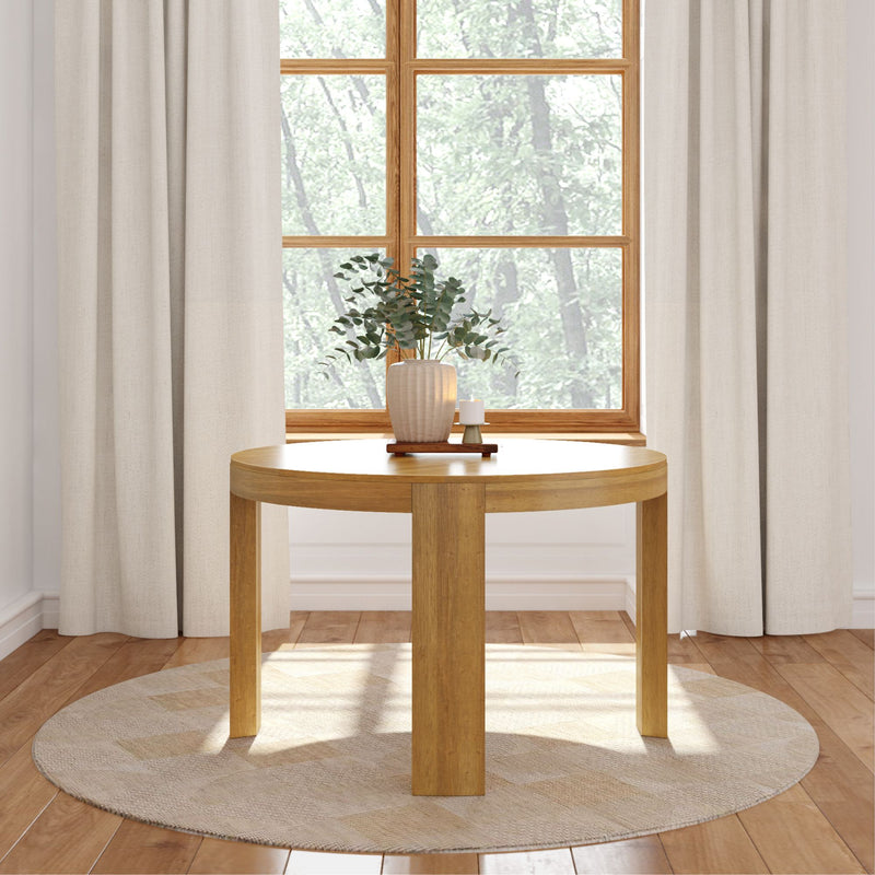 Round wooden table with modern decoration in a cozy room with natural light and elegant curtains.