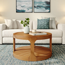 Modern living room with a stylish round wooden coffee table, comfortable beige sofa, decorative cushions, and abstract wall art.