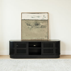 Modern black slatted media console TV stand with open shelving and framed neutral abstract painting in a minimalist living room