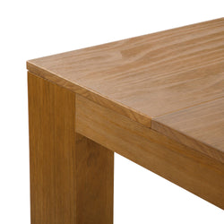 Close-up of solid oak dining table corner showing natural wood grain, light brown finish and sturdy square leg