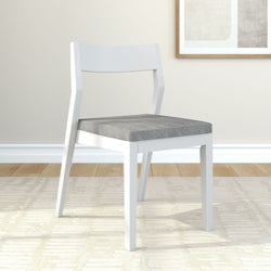 Modern white wooden chair with gray cushion in minimalist living room setting.
