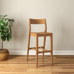 Wooden bar stool with a sleek design on hardwood floor next to a potted plant in a modern minimalist room.