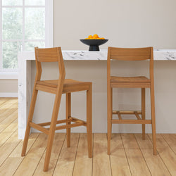 Two wooden bar stools at a marble kitchen island with a bowl of oranges, modern interior design.