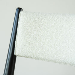 Close-up of cream boucle upholstered chair back with black wooden frame, modern dining chair upholstery texture