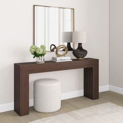 Modern hallway interior with dark wood console table, decorative mirror, round ottoman, contemporary lamp, and floral arrangement.