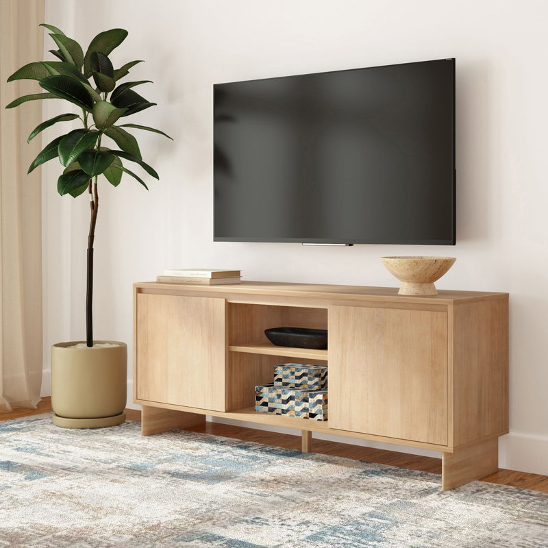 Modern living room with wall-mounted flat-screen TV above a light wood media console, minimalist decor, potted indoor plant and patterned area rug