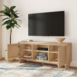 Modern living room with wall-mounted flat-screen TV above a light wood media console with open shelving and cabinets, decorative bowl, storage boxes, potted plant, and patterned area rug