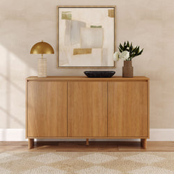 Minimalist modern wooden sideboard in a neutral entryway with a gold dome lamp, abstract framed art, black decorative bowl and vase of white flowers