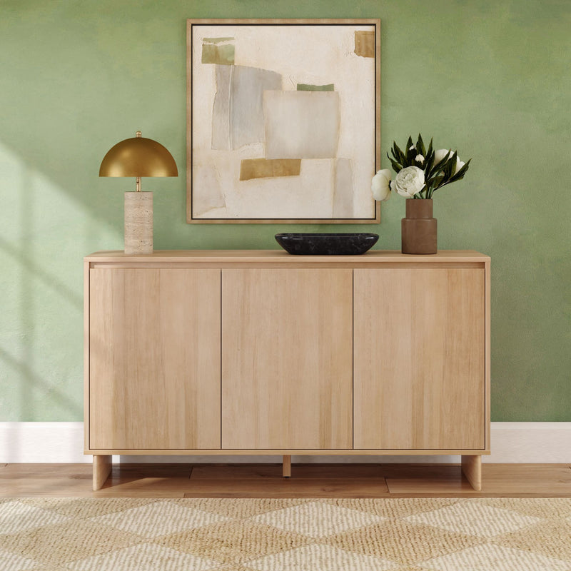 Light wood sideboard in modern Scandinavian entryway with sage green textured wall, abstract framed art, brass dome lamp, black decorative bowl and ceramic vase with white peonies on a neutral woven rug.