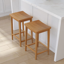 Two wooden bar stools with a natural finish by a white kitchen counter on a light wood floor.