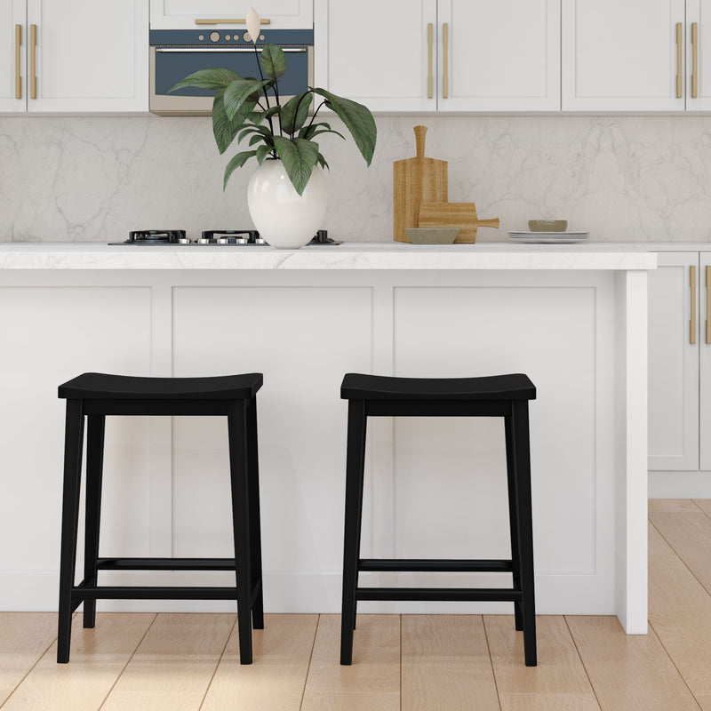 Black bar stools in a modern white kitchen with marble countertops and plant decor.