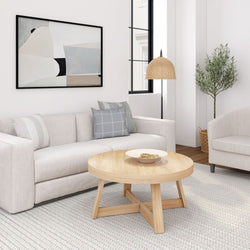 Modern neutral living room with beige sofa, light wood round coffee table, gray accent pillows, abstract wall art, rattan pendant lamp and potted olive tree on a textured rug