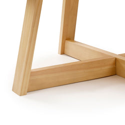 Light natural pine dining table base close-up showing angled legs and cross stretcher, solid wood construction with smooth finish in a modern farmhouse style