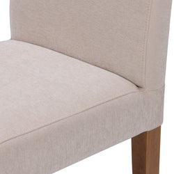 Close-up of light beige upholstered dining chair with padded seat and back, visible stitching detail and solid wood legs