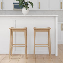 Minimalist kitchen design featuring two wooden bar stools and white cabinetry with marble countertops.