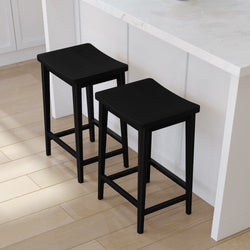 Black wooden bar stools with sleek design at white kitchen counter on light wood flooring.