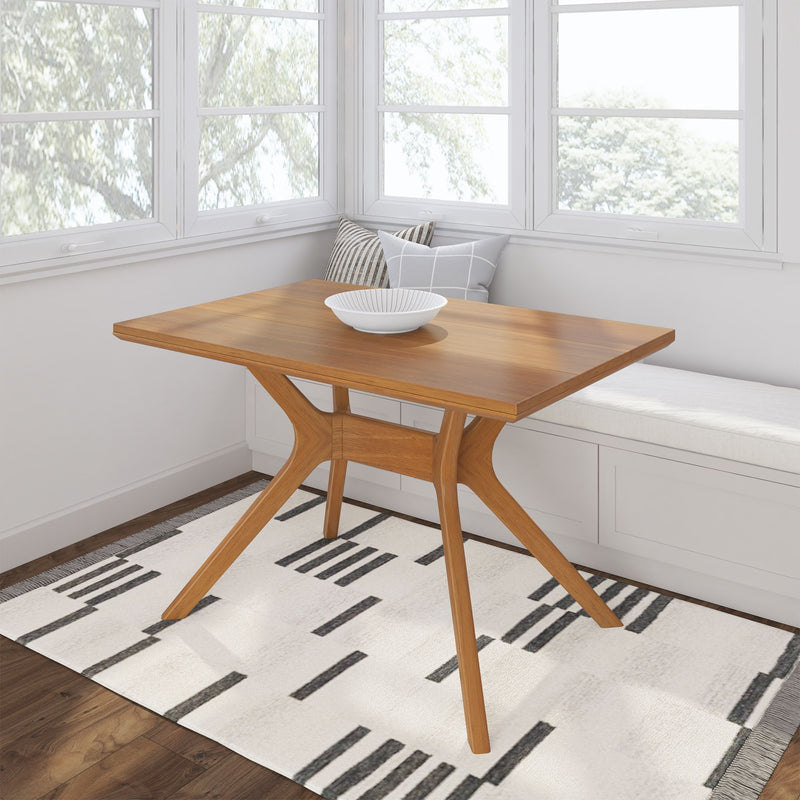 Modern wooden dining table in a bright room with large windows and geometric rug.
