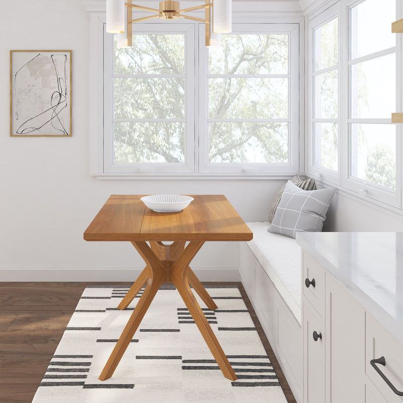 Modern dining nook with wooden table, geometric rug, and white built-in bench near large windows.