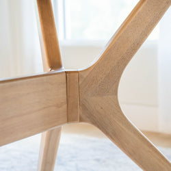 Close-up view of modern wooden table leg design in natural light.