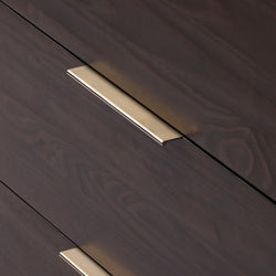 Close-up of dark walnut dresser drawers with brushed brass recessed handles, modern minimalist bedroom furniture