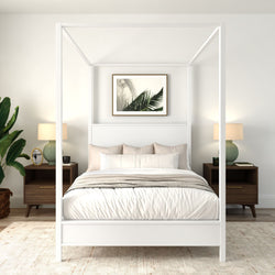 Modern minimalist bedroom with white four-poster canopy bed, neutral bedding, wooden nightstands, green table lamps, potted plant and framed palm leaf art