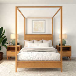 Modern wooden four-poster canopy bed in a minimalist neutral bedroom with matching mid-century nightstands, ceramic lamps, abstract wall art, and potted plant