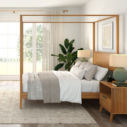 Bright modern Scandinavian master bedroom with light wood four‑poster canopy bed, neutral linen bedding, wooden nightstand with lamp, large window with sheer curtains and indoor plant.