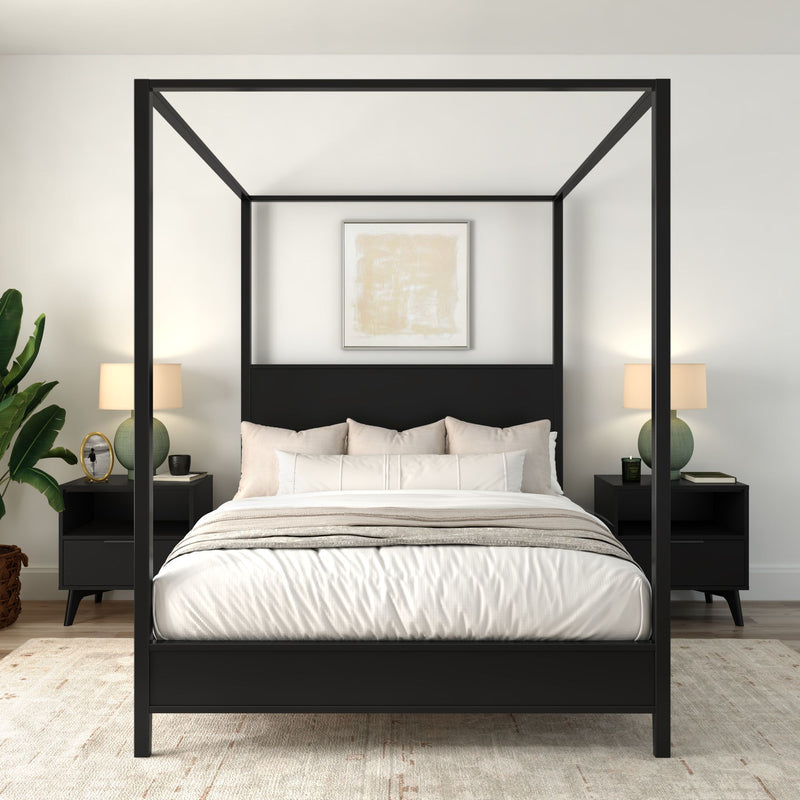 Modern minimalist master bedroom with black four-poster canopy bed, neutral bedding, matching nightstands, table lamps and potted plant.