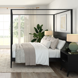 Modern master bedroom with black four-poster canopy bed, neutral bedding, bedside lamps, indoor potted plant and large sunlit window
