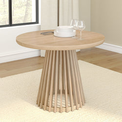 Modern round wooden dining table with unique base design in a sunlit room.