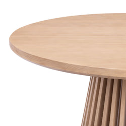 Modern round wooden dining table with fluted base design.