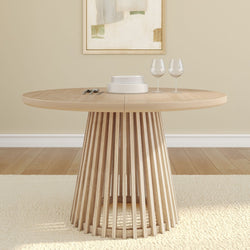 Round wooden dining table with modern slatted base, adorned with white plates and wine glasses in a cozy dining room.