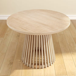 Round wooden dining table with modern slatted base on hardwood floor.