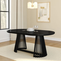 Black modern oval dining table with slatted pedestal base in a neutral contemporary dining room with hardwood floors, cream rug, pendant light, stacked white plates and wine glasses