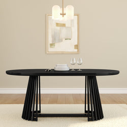 Modern black oval dining table with slatted pedestal base, stacked white plates and two wine glasses in a beige dining room with abstract wall art and pendant light
