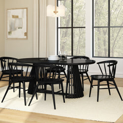 Modern black round dining table set with six spindle-back chairs in a Scandinavian farmhouse dining room with large windows, cream rug and hardwood floor