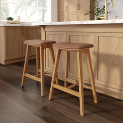 Wooden bar stools with leather seats in a stylish kitchen setting.