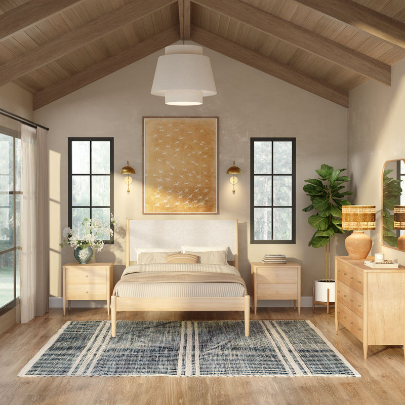 Modern farmhouse bedroom with vaulted wood-beam ceiling, light wood bed, matching nightstands, neutral linens and black-framed windows