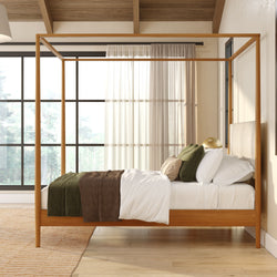 Modern wooden four-poster bed in neutral bedroom with large windows and natural light