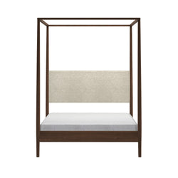 Modern walnut four-post canopy bed with beige upholstered headboard and low platform base, white mattress, isolated on white background
