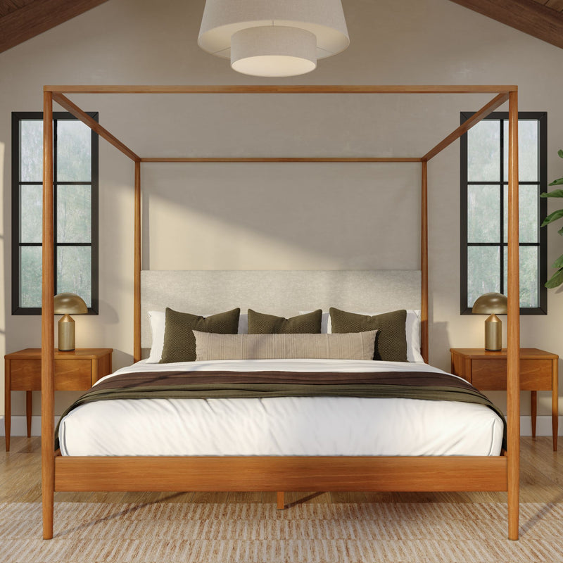 Minimalist bedroom interior with wooden four‑poster canopy bed, neutral white and beige bedding, olive accent pillows, mid-century nightstands with brass lamps and large windows providing natural light