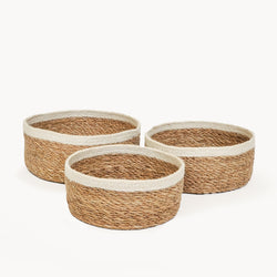 Three round natural woven baskets with white trim, perfect for home storage and decor.