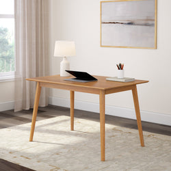 Modern wooden desk with a laptop and lamp in a minimalist home office setting.