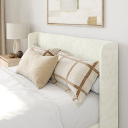 Modern bedroom with upholstered headboard, patterned pillows, and minimalist decor.