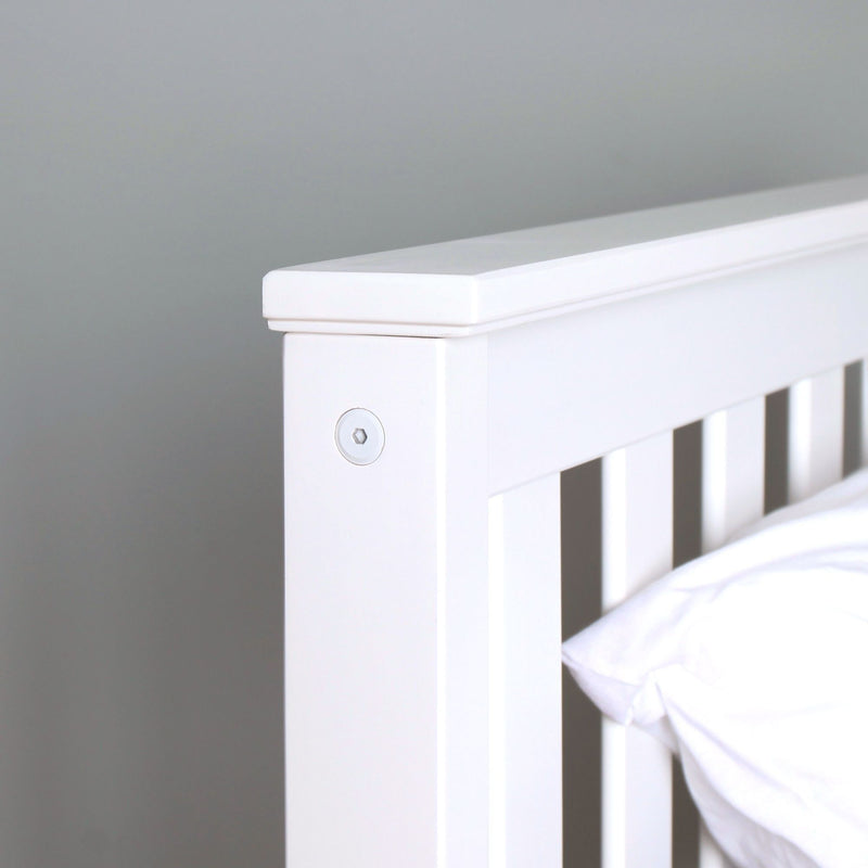 Close-up of white wooden slatted bed headboard with smooth painted finish and pillow, modern minimalist bedroom decor