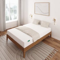 Modern bedroom with a white memory foam mattress on a wooden bed frame, featuring geometric wall art and cozy lighting.