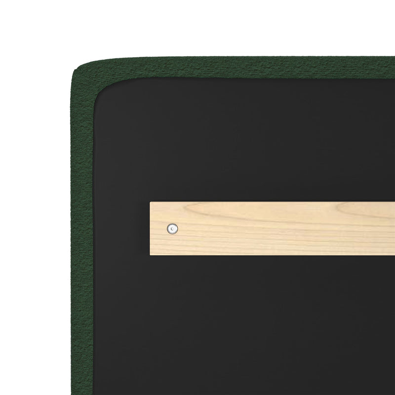 Close-up of green upholstered headboard corner showing textured fabric edge, black backing panel and wooden mounting bracket with metal screw