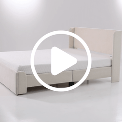 Beige upholstered platform bed with low-profile headboard and mattress on a white floor, modern minimalist bedroom furniture